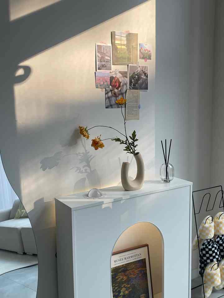 Warm sunlight fills a white and natural toned space featuring a console cabinet with posters on the wall, creating a cozy atmosphere