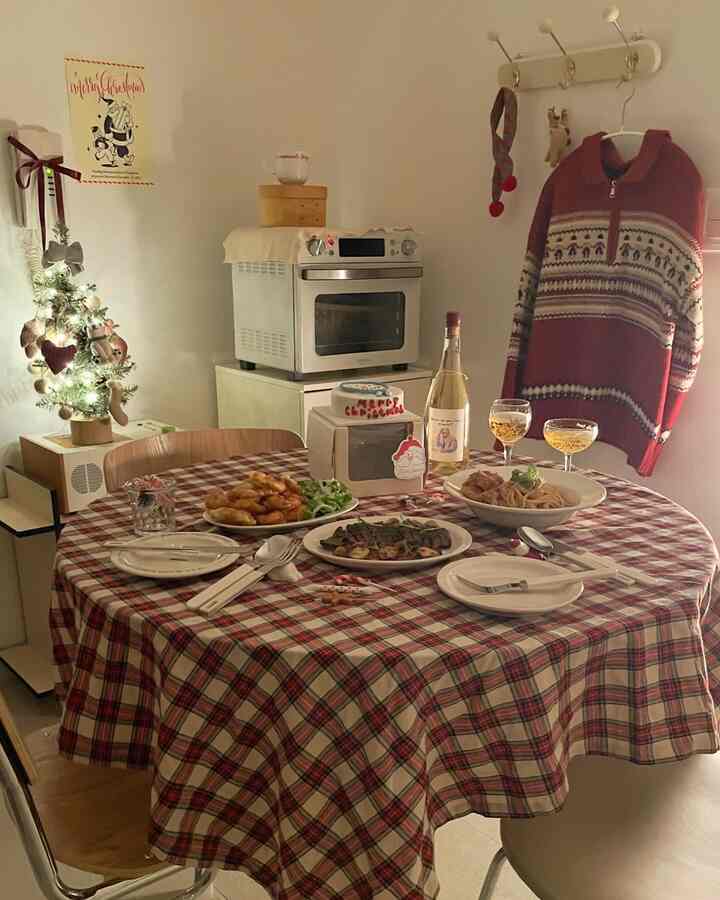 赤と白の色調のキッチンスペース、クリスマスの装飾と料理が置かれた丸いダイニングテーブルが温かみのあるホームパーティーの雰囲気を醸し出しているインテリア
