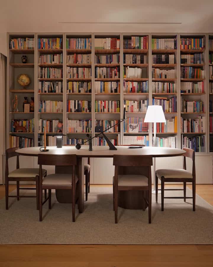 Cozy natural modern study space in warm brown and beige tones featuring a walnut table and day chairs with wood bookshelves