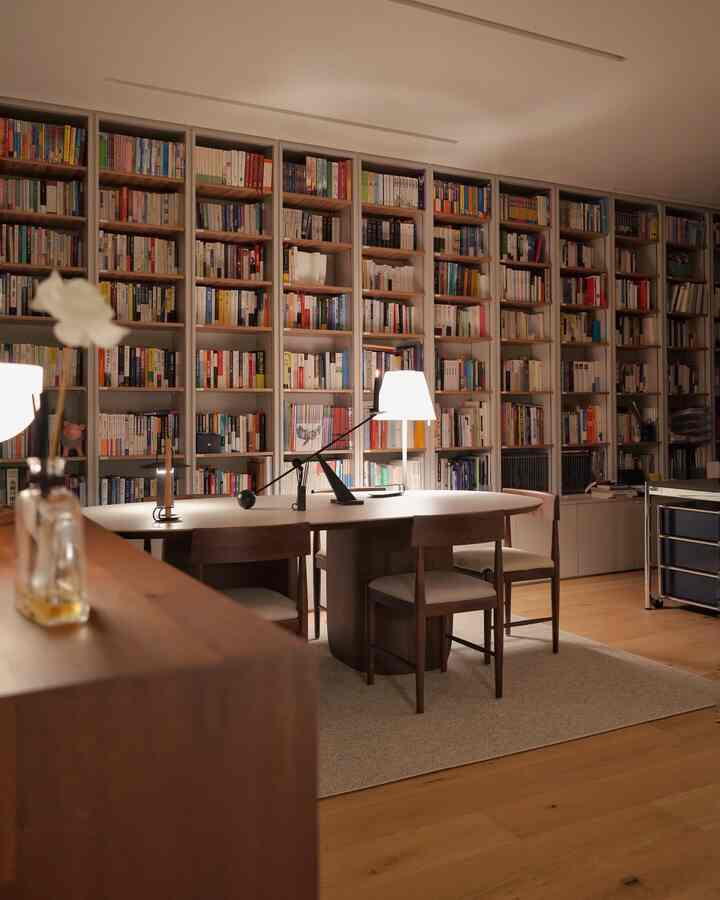 Warm wood-tone study featuring expansive bookshelves, day chairs, and a cozy home office atmosphere