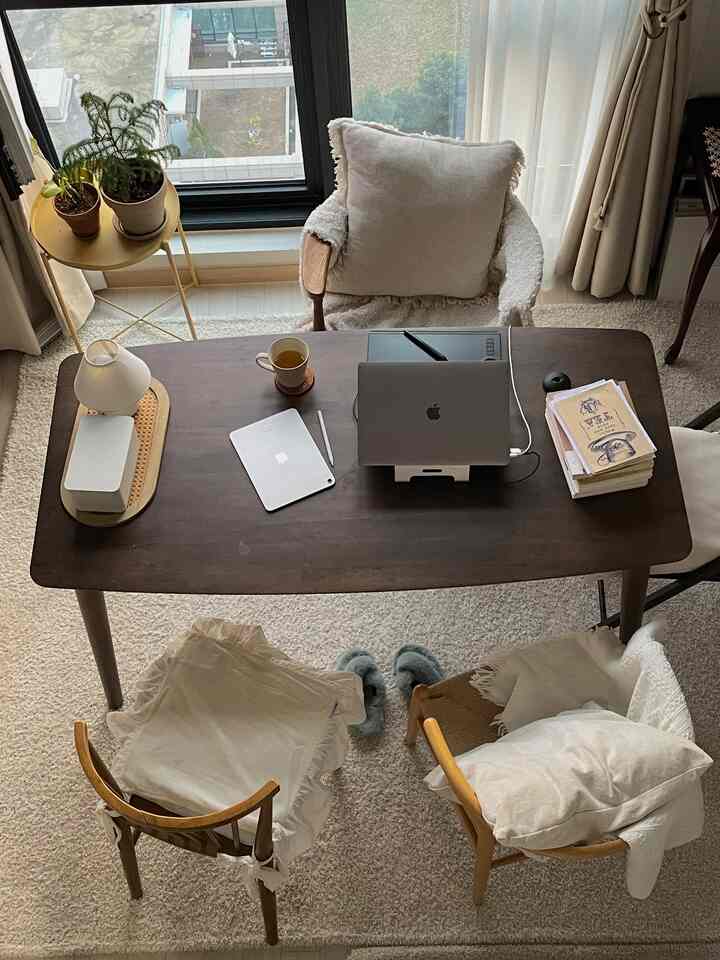 Natural tone home office space with dark wooden desk featuring laptop and tablet, creating a cozy workspace