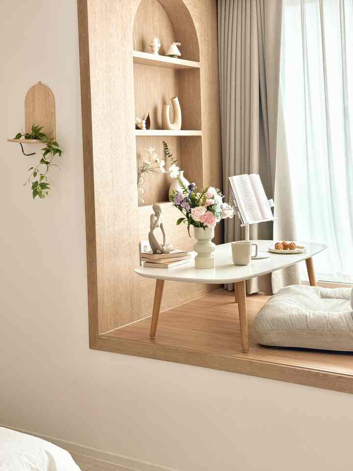 ナチュラルな木目調とベージュのカーテンが調和した、花瓶とフロアクッションのある落ち着いた空間