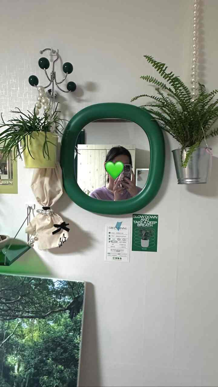 緑色の丸いフレームミラーと複数の植物が白い壁に飾られた居心地の良いインテリア空間