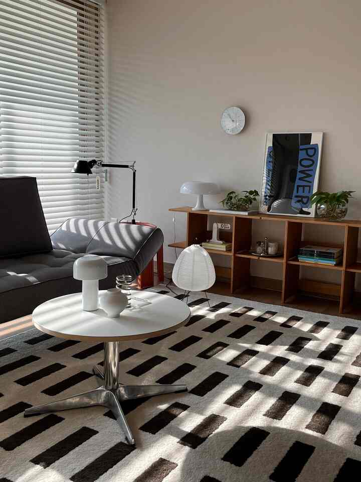 グレーのソファと白い円形テーブル、木製棚が配置されたナチュラルな色調のリビングルーム