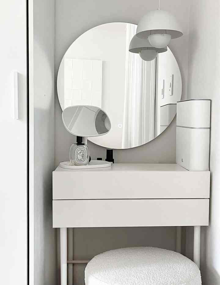 白を基調としたトイレ空間、丸い鏡とシンプルな化粧台が配置された印象的な雰囲気のあるインテリア