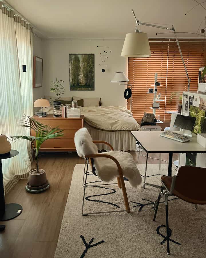 A cozy studio apartment in natural beige tones featuring a bedroom and a home office setup