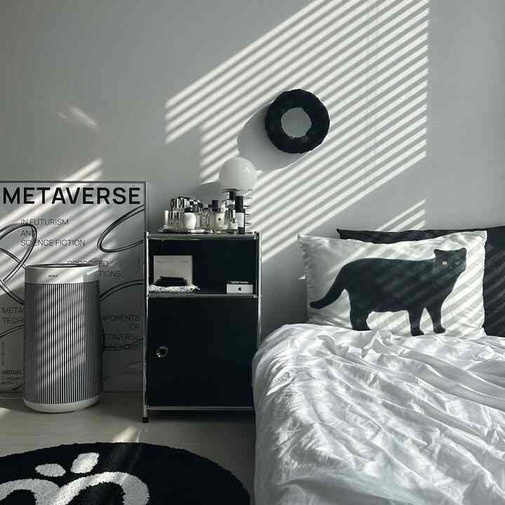 Black and white toned bedroom featuring a cat pillow cover and Metaverse poster, creating a modern atmosphere