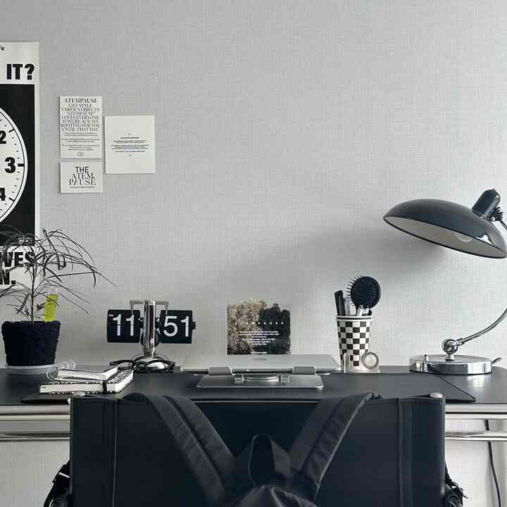 Charcoal and black toned home office desk featuring mid-century modern furniture and lighting in a tidy setting