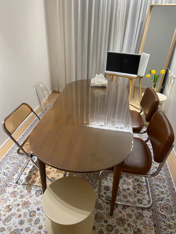 暖かみのあるブラウンと透明な椅子が配置された小さなダイニングルーム、モダンなダイニングテーブルとラグが印象的な雰囲気のある空間