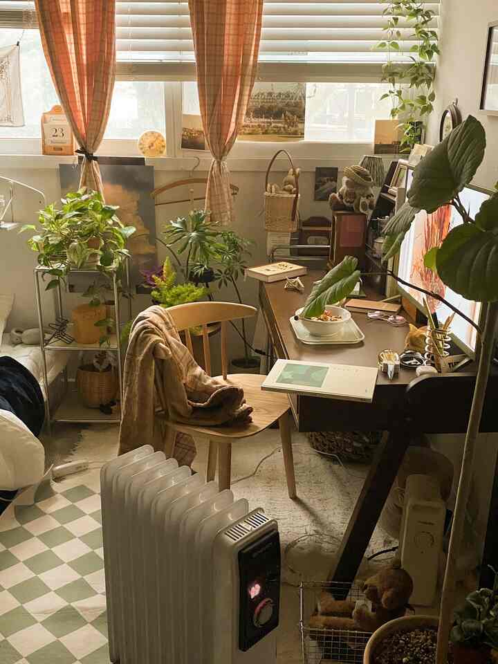 木目調と多様な緑の植物が配されたホームオフィス、中央にウッドデスクとチェアが配置された温かみのある空間