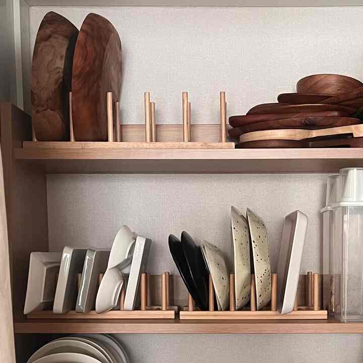 木目調の棚に様々な皿やボウルがオストビットの木製皿立てに整然と収納された、清潔感のあるキッチン空間