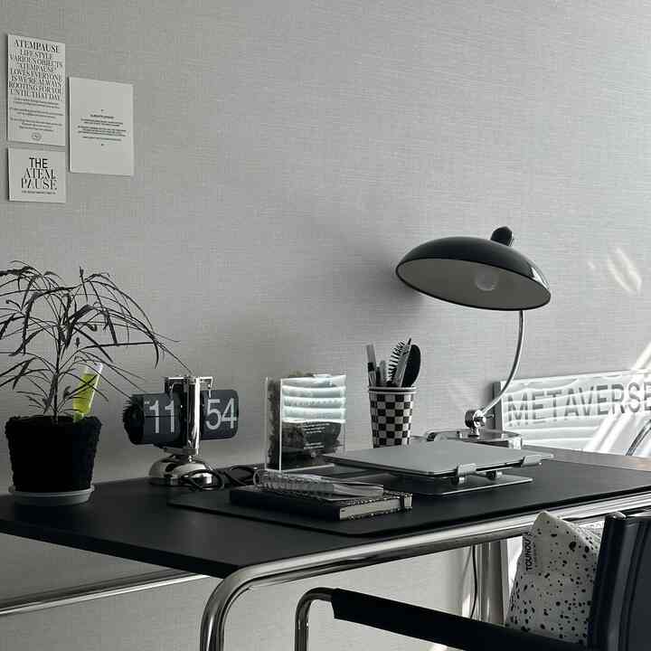 グレーの壁と黒のモダンなデスク、デスクランプや植物が配置された整理されたホームオフィス空間