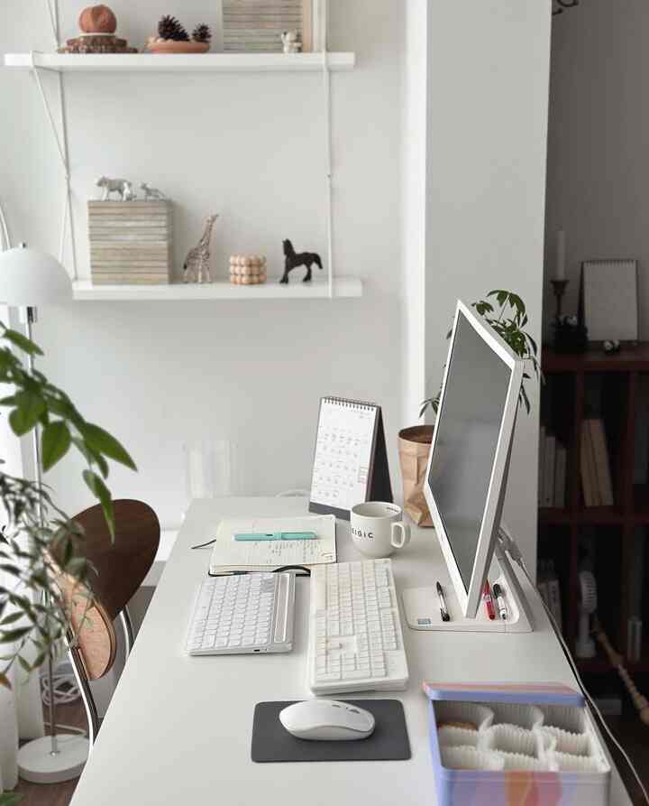 White-toned home office featuring a clean desk and monitor with a simple, organized workspace