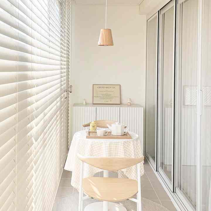 Soft white and natural wood tone veranda home cafe featuring wooden furniture and blinds in cozy space