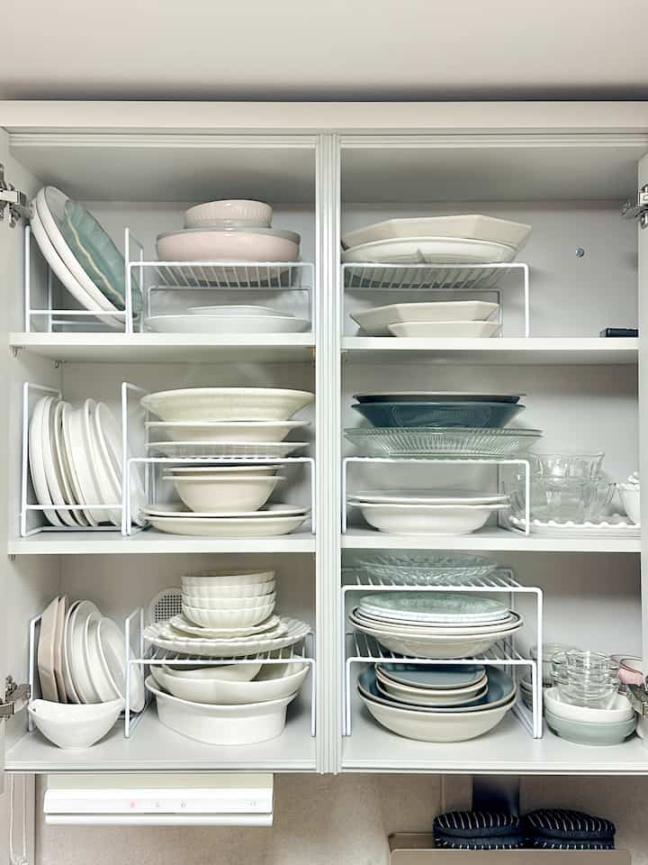 ホワイトトーンのキッチン収納棚に、横置きと縦置きの皿ラックで整頓された皿とボウルが配置されたきれいなインテリア