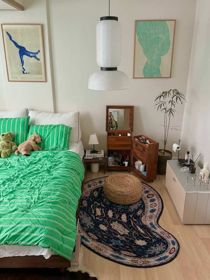 Cozy bedroom with white walls, natural wood furniture, and vibrant green bedding