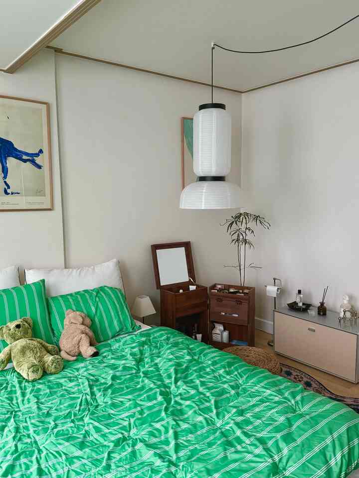 A white and natural tone bedroom featuring green striped bedding and wooden furniture, creating a cozy and natural atmosphere