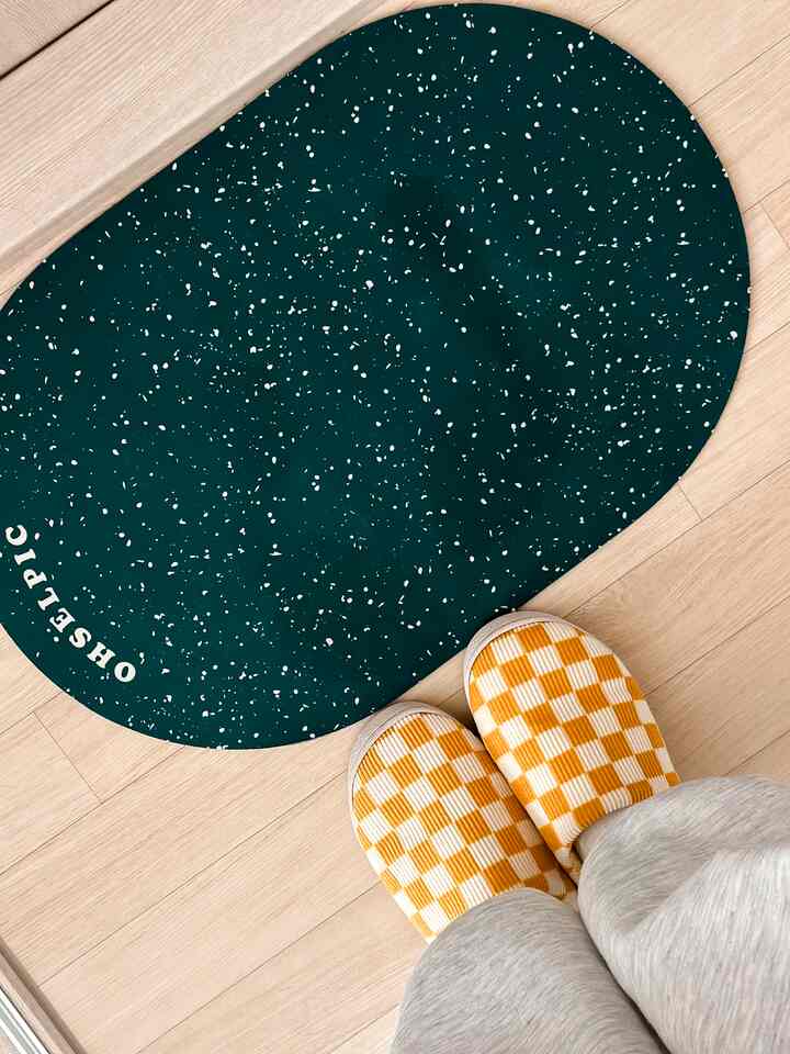 ナチュラルな木目調の床に深緑色のバスマットと黄色いチェッカーボード柄のスリッパが並べられた玄関付近のバスルーム