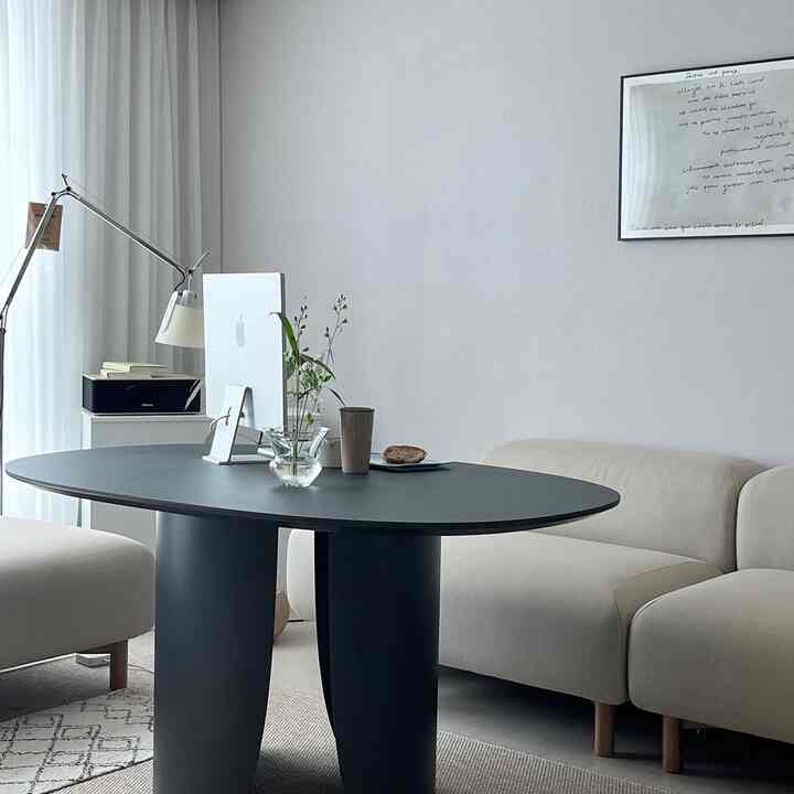A white and black toned living room featuring a modern sofa and large coffee table with a simple atmosphere