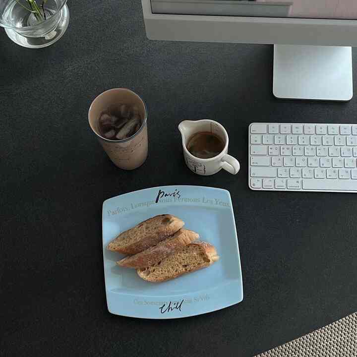 A modern black-toned living room table set with an iMac, coffee, and bread plate creating a cozy home office atmosphere
