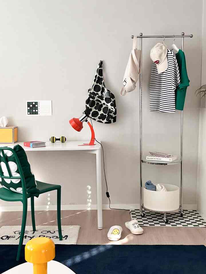White and green simple small room home office featuring desk and clothes rack with a clean atmosphere