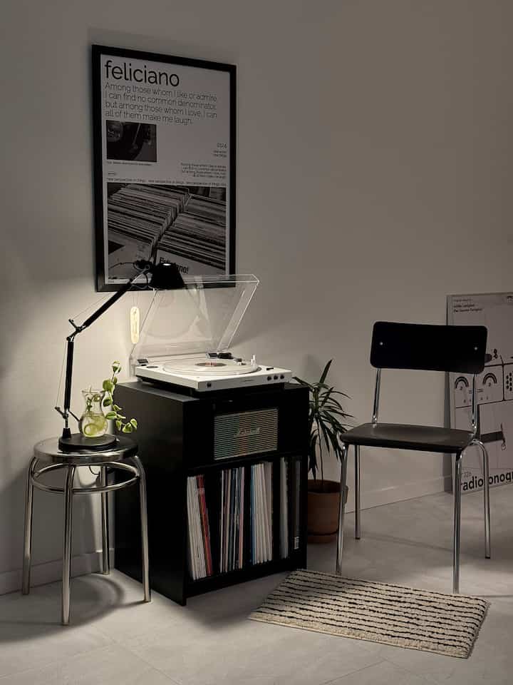モノトーンとブラックが基調のワンルーム音楽鑑賞スペース、ターンテーブルとLP収納が配置されたシンプルモダンなインテリア