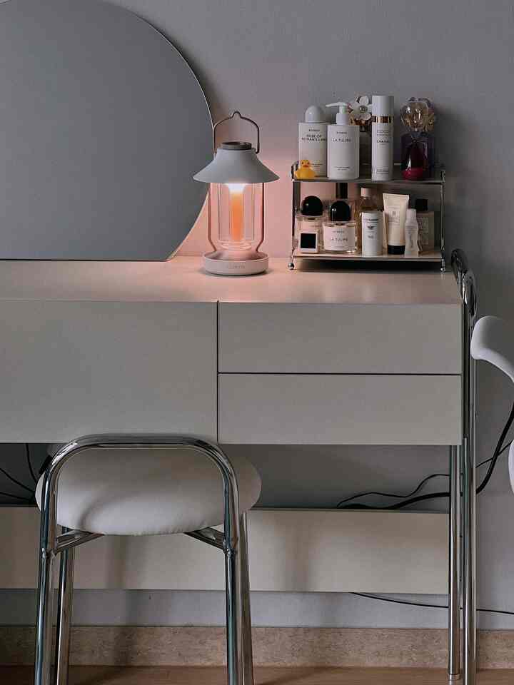 ホワイトでミニマルなワンルームの化粧台空間、照明と化粧品棚が配置されたすっきりとしたインテリア