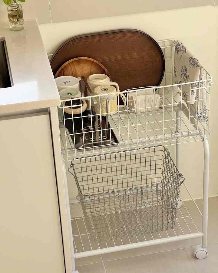 ホワイトとウッドトーンのキッチン空間、スチール製隙間収納ラックにカップとトレイが整然と配置された清潔感あるインテリア