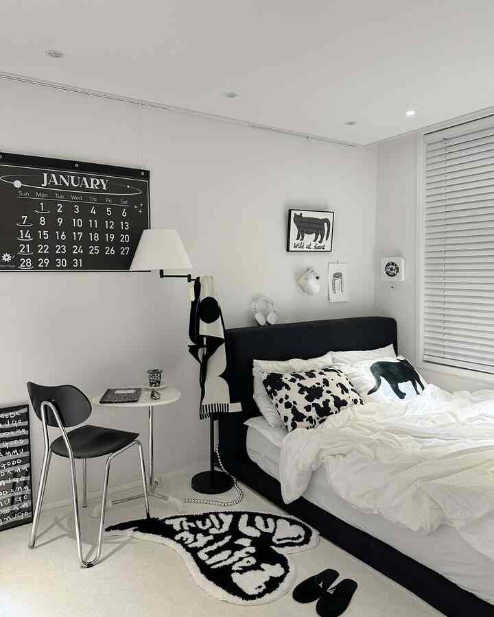 モノトーンの黒と白の小さな寝室、黒いベッドとラグ、フロアランプが配置されたミニマルなインテリア
