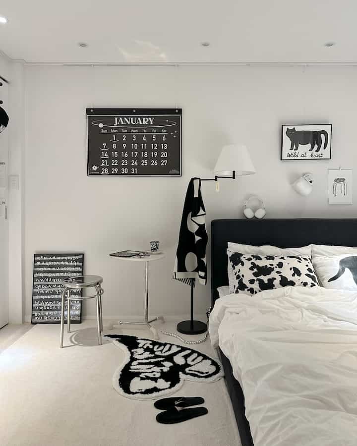 モノトーンの黒と白の寝室、サイドテーブルとスツールが配置されたモダンで整った空間