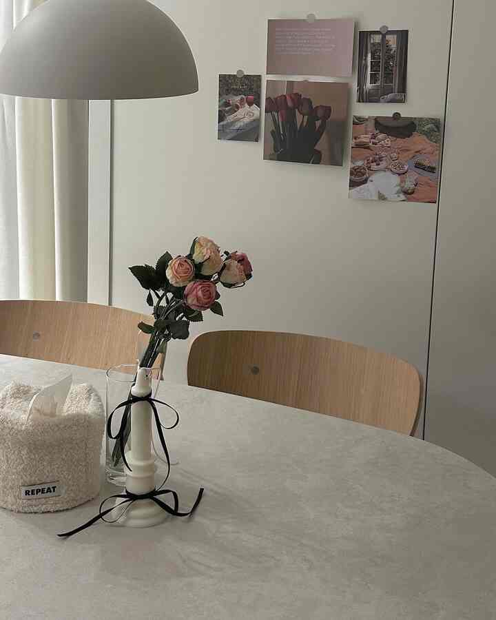 ベージュ色調のダイニングルーム、ナチュラルな木製チェアと花瓶、キャンドルが置かれたシンプルなインテリア