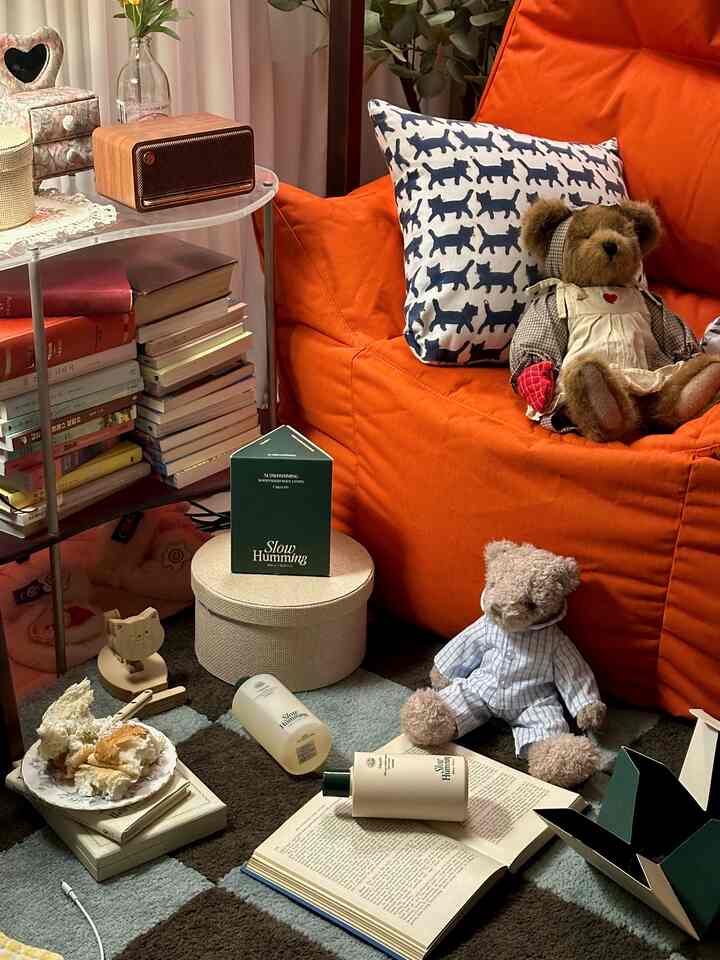 Cozy living room featuring a dominant orange bean bag with cat-patterned cushions, complemented by a multicolored rug and teddy bears creating a warm atmosphere
