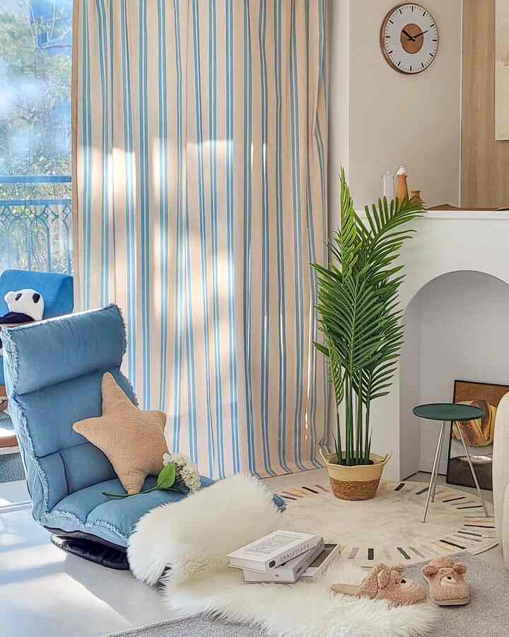 アイボリーの色調のリビング、ブルーのクッションチェアと植物が配置されたシンプルで自然な雰囲気のインテリア