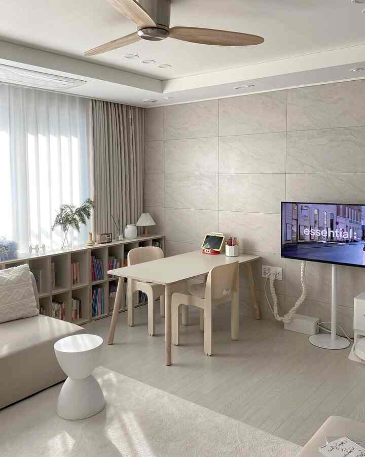 ホワイトとベージュの色調のリビング書斎、低い本棚とファミリーデスクが配置されたシンプルで自然なモダンな雰囲気のインテリア