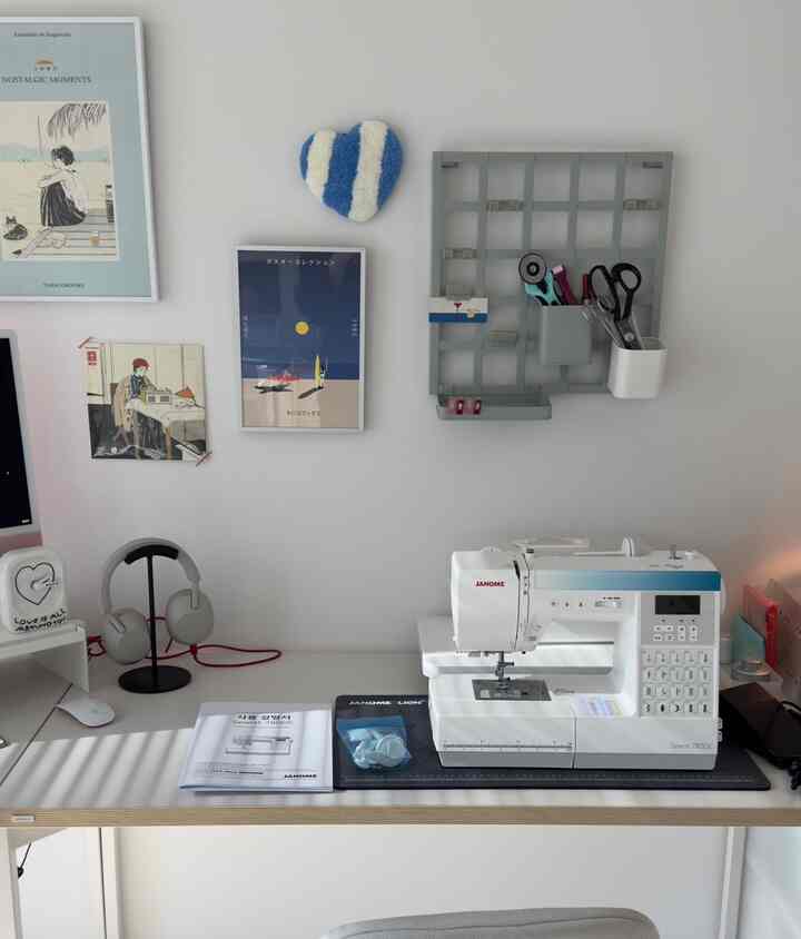 White-toned sewing room workspace featuring a Janome sewing machine and tidy desk in a minimalist setting