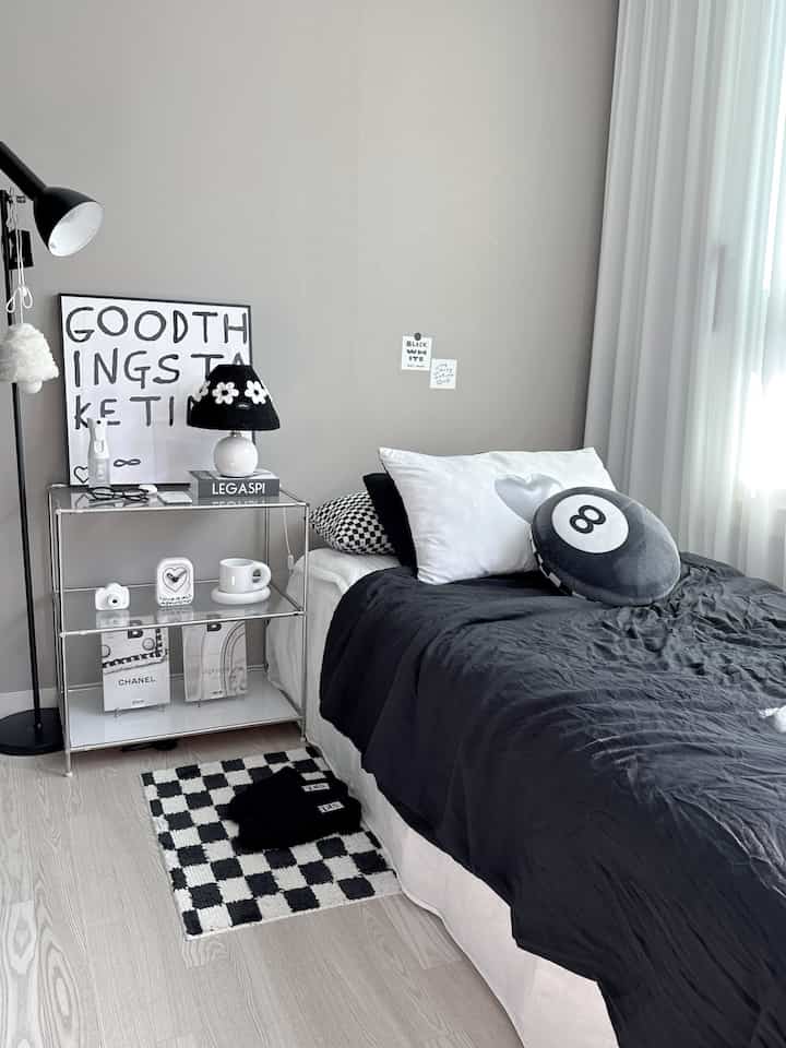 モノトーンのワンルーム寝室、白黒の寝具とチェッカーボード柄のラグが配置されたシンプルモダンな空間