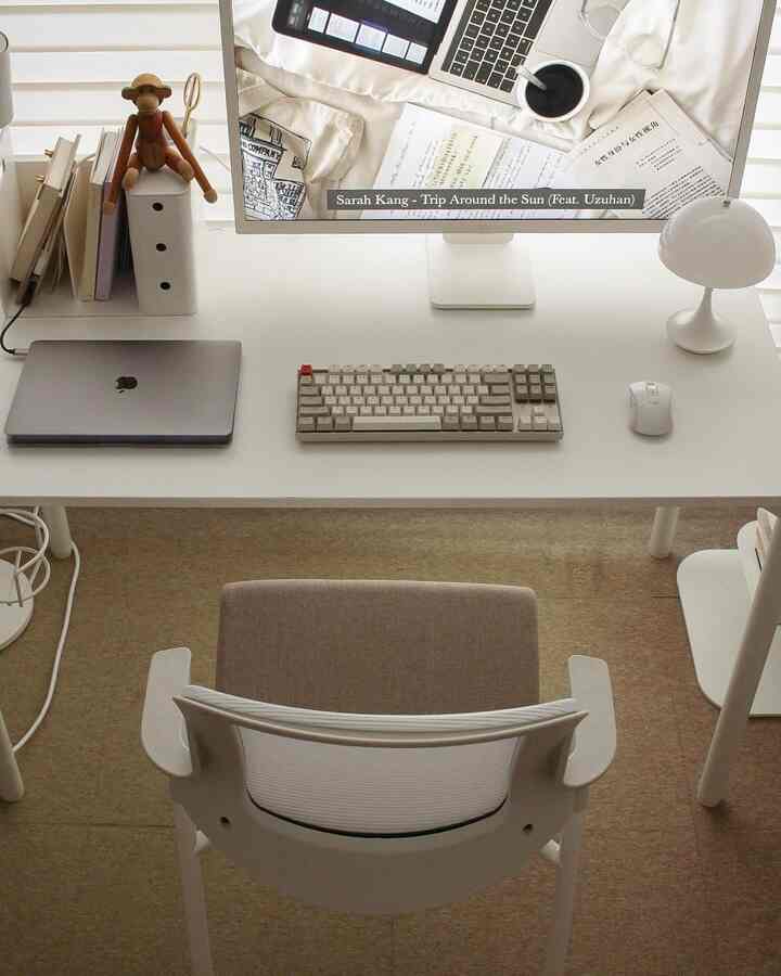 Modern white-toned home office space featuring desk with monitor, keyboard, and laptop in a clean workspace