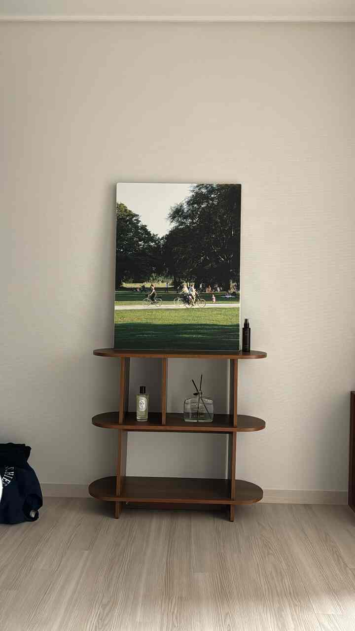 ナチュラルトーンの壁と木目調の棚、ディフューザーとアートプリントが配置された整然とした空間