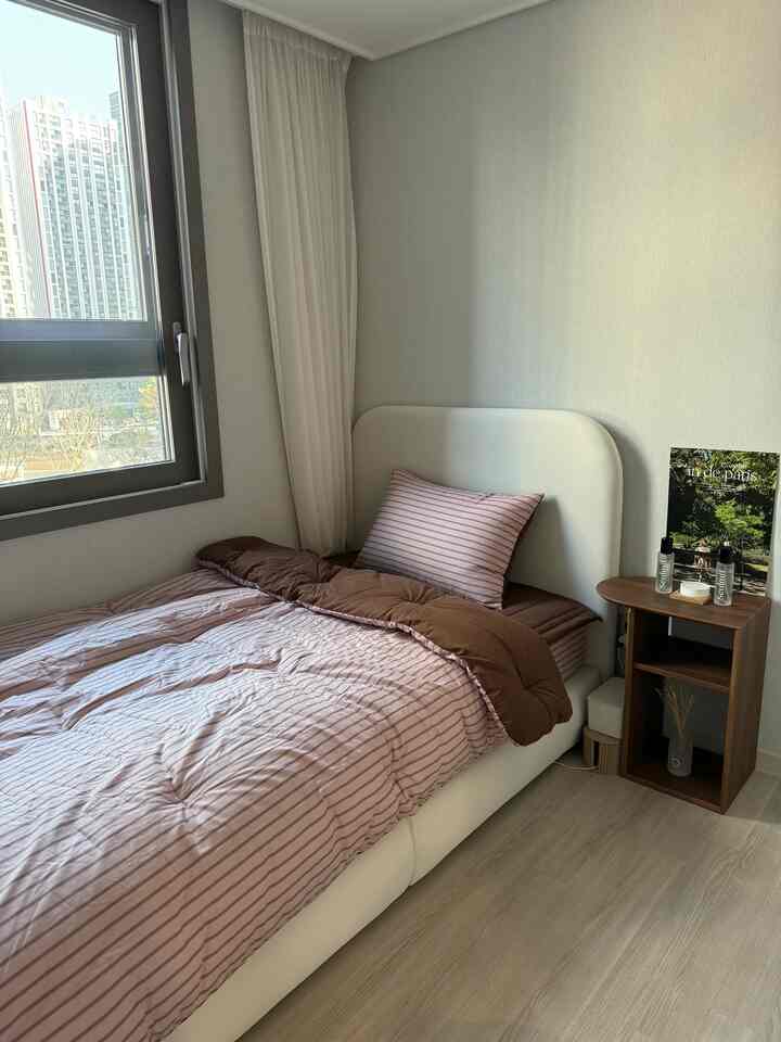 ホワイトとブラウンが調和した一人用寝室、ベッドフレームとナイトテーブルが配置されたナチュラルモダンな空間