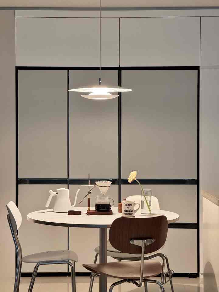 White and wood-toned kitchen space featuring a round dining table with drip coffee set creating a cozy home cafe atmosphere