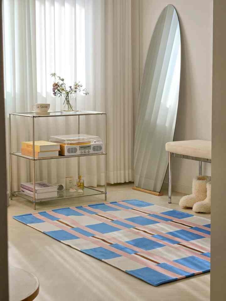 Beige and blue toned balcony space featuring a rug, side table, and large full-length mirror in a simple and natural atmosphere