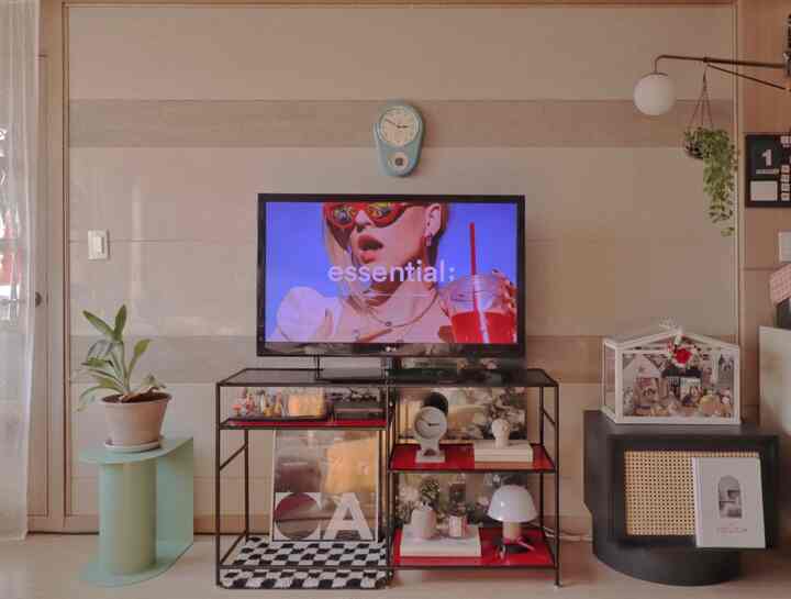 Soft beige toned living room featuring a TV on metal stand, mint side table with plant on left, creating a vintage atmosphere