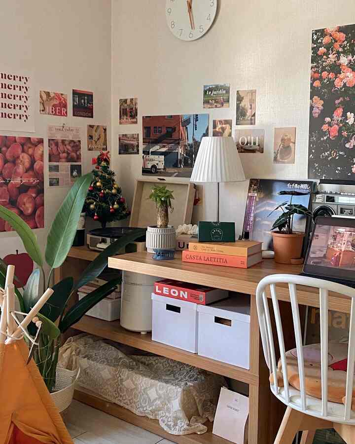Cozy home office desk with natural wood tones and white accents, decorated with colorful posters and plants