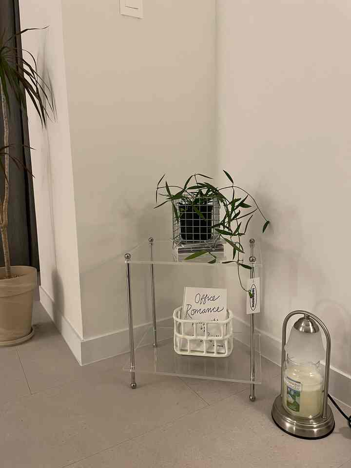 ホワイトと透明アクリル素材が調和したコーナースペース、植物と多用途バスケットを配したミニマルでモダンなインテリア