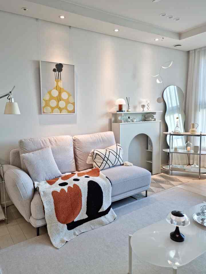 ホワイトとベージュの色調のリビングルーム、モダンなソファとミッドセンチュリーモダンスタイルのスローが配置された雰囲気のある空間