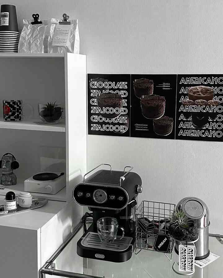 ブラックとシルバーのトーンのワンルーム、コーヒーマシンとコーヒーポスターが配置されたモダンなホームカフェインテリア