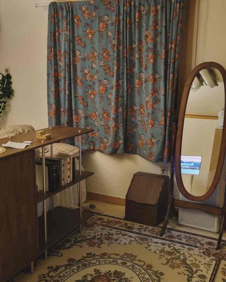 茶色のアンティーク家具と花柄のカーテン、カーペットがあるワンルームの印象的な空間