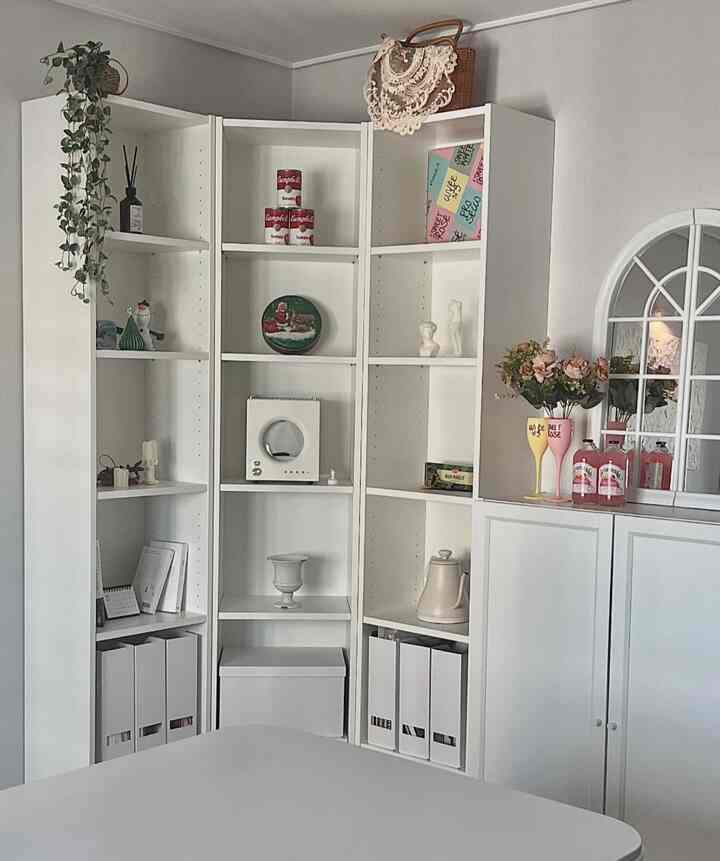 A white-toned dining room featuring IKEA Billy corner storage and a clean dining table creating a harmonious space
