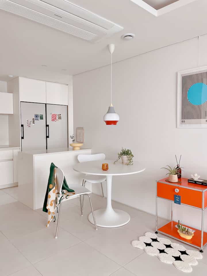 白を基調としたキッチン、丸テーブルとサイドテーブル、ニットブランケットとラグが配置されたモダンな雰囲気のインテリア