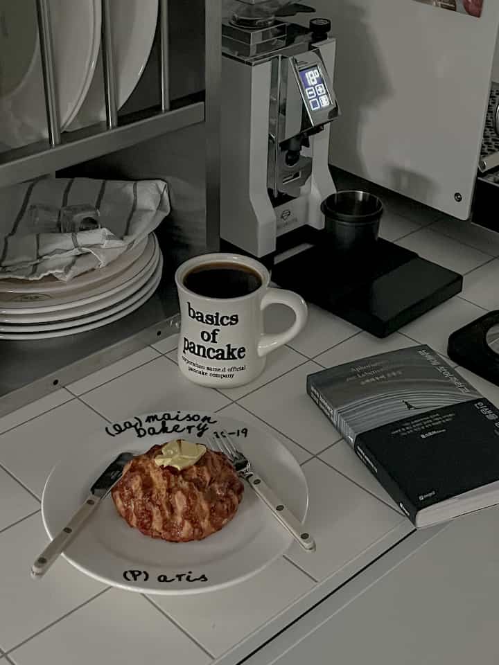 モノトーンのホワイトタイルキッチン、コーヒーグラインダーやマグカップ、ベーカリープレートが配置された雰囲気のあるおうちカフェ